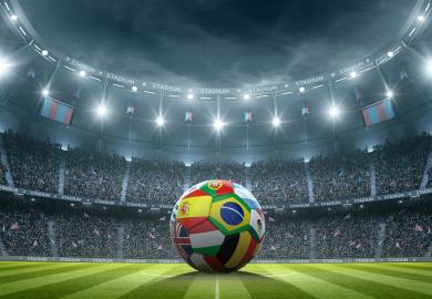 Football painted with different countries' flags, in the centre of a football stadium