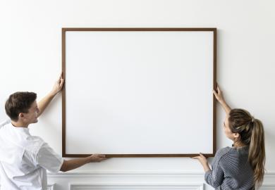Man and woman hanging blank framed canvas on wall