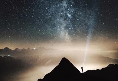 A man shining a torch up to the stars