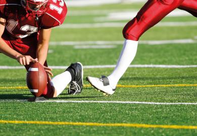 American football player preparing to kick ball