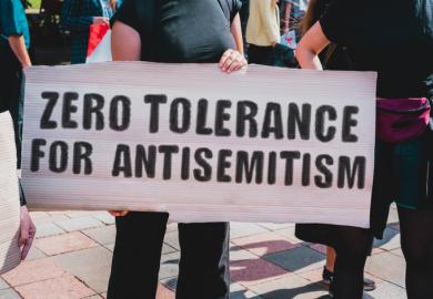 A woman hold a "zero tolerance to antisemitism" sign
