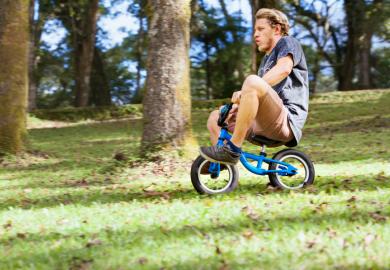 A man rides a child's bicycle, illustrating the need for growth