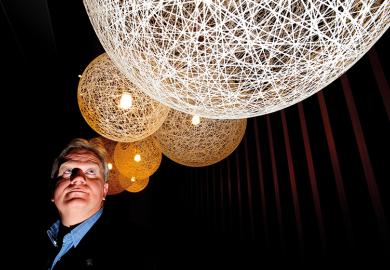 Nobel laureate Brian Schmidt looking up at lit up spheres