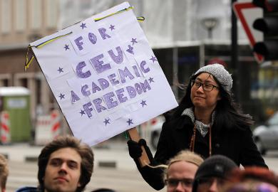 Woman holds a placard in support of academic freedom at CEU