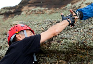 Climber being helped to climb mountain