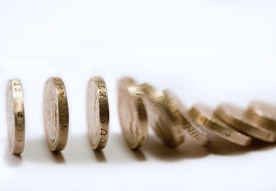 Pound coins falling like dominoes, illustrating funding precarity