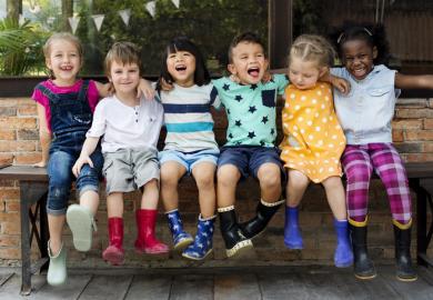 Children in wellington boots, arm in arm, representing collegiality in higher education