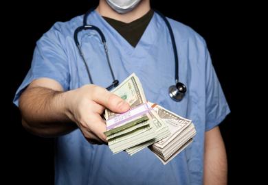 Male doctor holding out bank notes