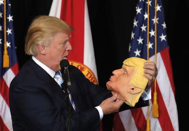 Donald Trump holding mask of his own face
