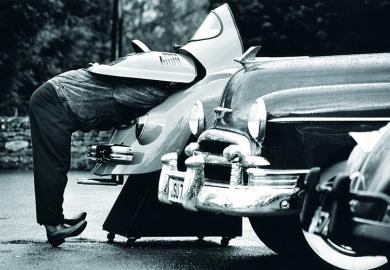 man looks under car bonnet