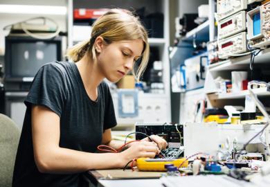 Female engineer measuring voltage on conductor board