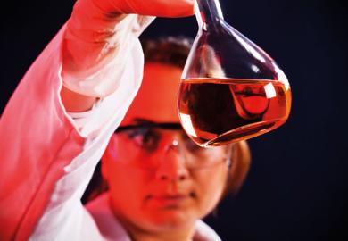 Female scientist examining flask of liquid