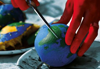 Cutting an orange painted like a globe representing funding cuts