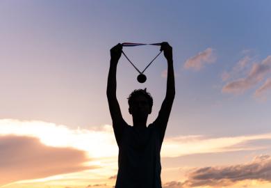 An athlete holds up their medal, illustratiung TEF ratings