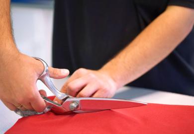 Hand cutting red cloth with scissors