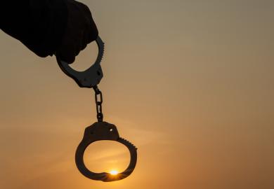 A person holding up handcuffs in the sunrise, symbolising autonomy