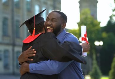A cheerful father and graduating son hugging