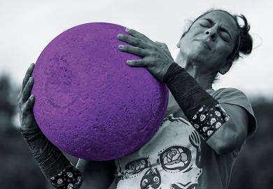 woman lifts heavy ball