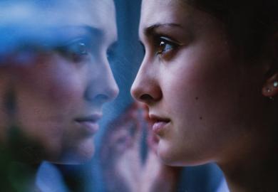 A woman stares at herself in the mirror, illustrating universities' role in shaping national identity
