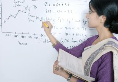 An Indian academic writes formulas on a whiteboard