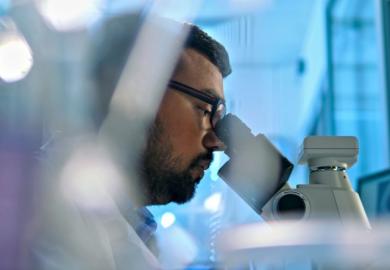 An Indian scientist looks through a microscope