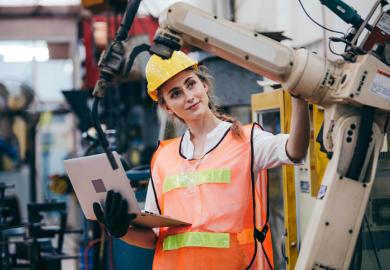 An industry robot is adjusted by an engineer illustrating an op-ed about industry-university collaboration