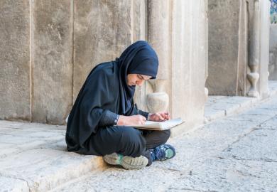 An Iranian student sits on the ground, illustrating inequliaty in university entrance