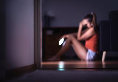A student reacts with sadness to her mobile phone - online safeguarding should be higher up university agendas