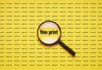 Fine print enlarged with magnifying glass illustrating that academics should read and understand publishing contracts