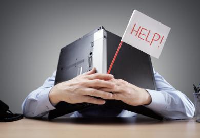 A man covers his head with his laptop and holds a flag that says 'Help!'