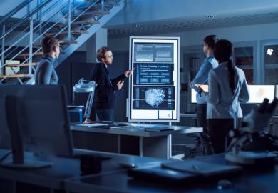 People in a lab meeting look at screens