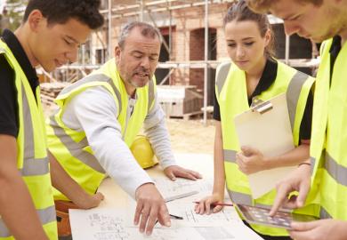 Young builders study blueprint on a building site, illustrating workplace learning