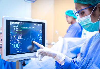 A surgeon watches as a line on a monitor spikes downwards, symbolising cuts to health research