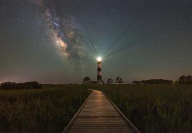 A lighthouse shines at night, illustrating community engagment