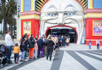 People queue at the entrance to Luna Park, Melbourne, symbolising widening access