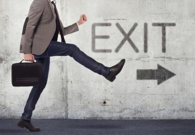 Male academic walking in direction of exit sign