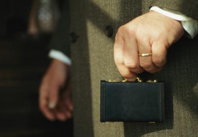 Man holding tiny briefcase between finger and thumb