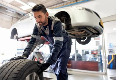 A mechanic removes the wheels of a car, symbolising the sacking of teaching staff