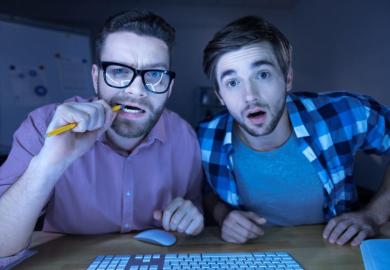 Men peering confused into computer screen