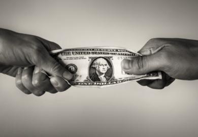 People pull on a dollar bill, illustrating competition for resources