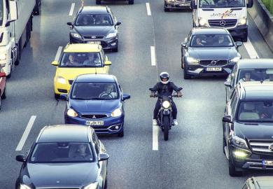 A motorbike slips through a traffic jam, symbolising rapid completion of a PhD