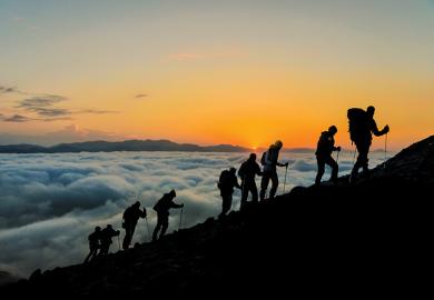 people climbing mountain with mist below