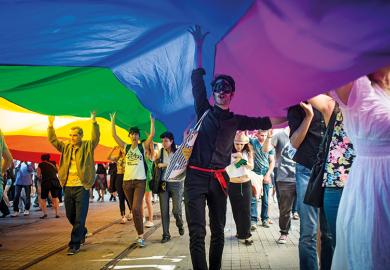 A protester in a mask holds up a Gay Pride flag during the annual Trans-sexual march on Istanbul's Istiklal Caddesi 