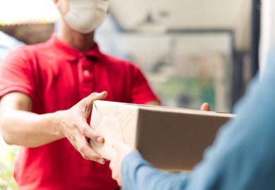 A shopworker hands over a brown parcel to a customer