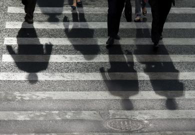 People's shadows cast on road crossing