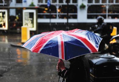 Person walking in rain carrying Union Jack umbrella