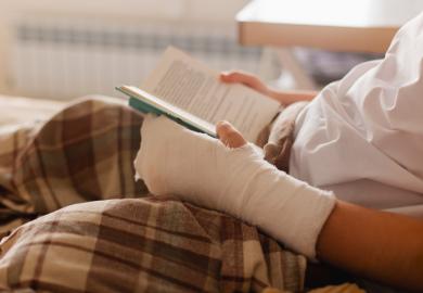 A person reads a book with a bandaged arm, symbolising the scarring PhD experience