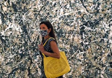 Woman in mask walking past a Pollock painting