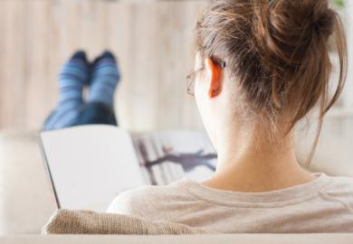 A woman reading a book with her feet up