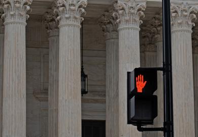Red hand stop sign in from of classical columns to illustrate that serious abuses should stop being investigated only by universities.